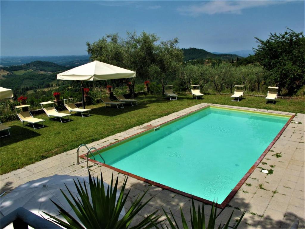 a swimming pool with chairs and an umbrella at Apartment Rustico by Interhome in Linari