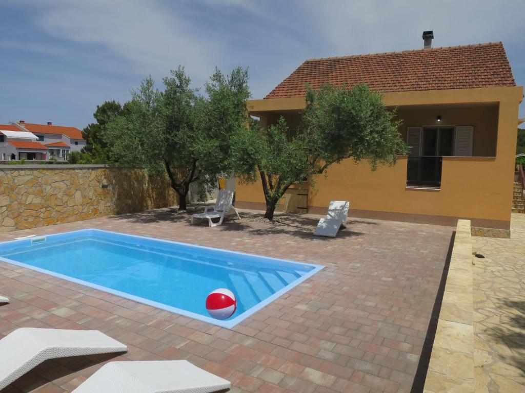a pool in front of a house with a red ball at Holiday Home Tina - BIG120 by Interhome in Biograd na Moru