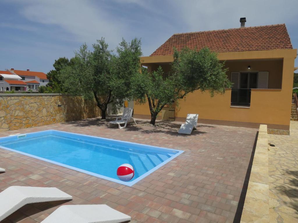a pool in front of a house with a red ball at Holiday Home Tina by Interhome in Biograd na Moru