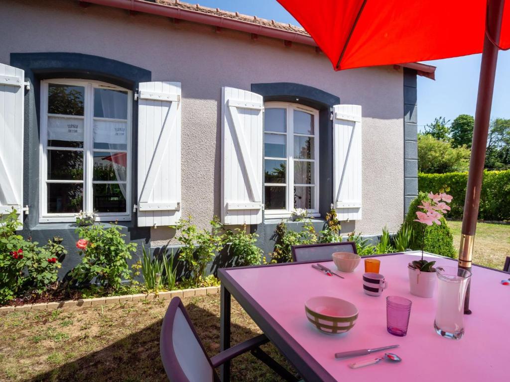 een roze tafel met stoelen en een paraplu voor een huis bij Holiday Home La Gare by Interhome in Champeaux