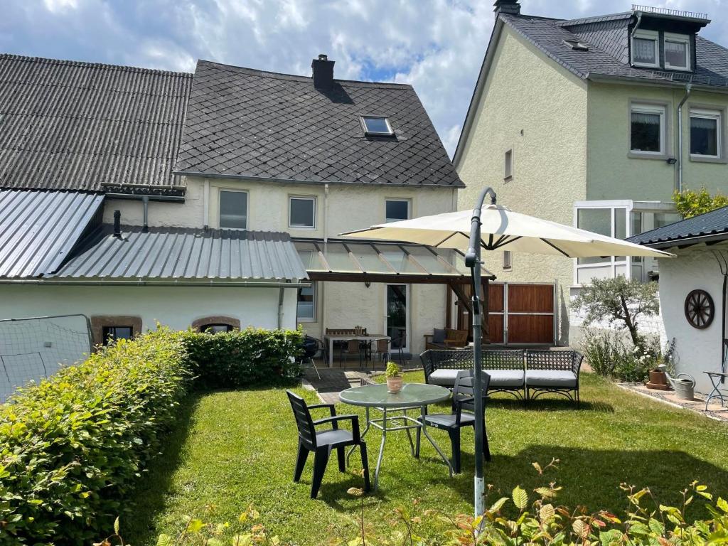 een achtertuin met een tafel en stoelen en een parasol bij Holiday Home Bruni by Interhome in Manderscheid