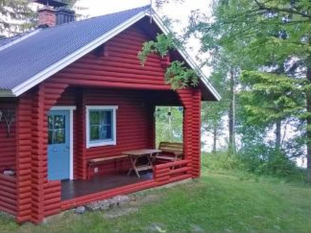 a red cabin with a picnic table in a yard at Holiday Home Koivuranta by Interhome in Petäjävesi