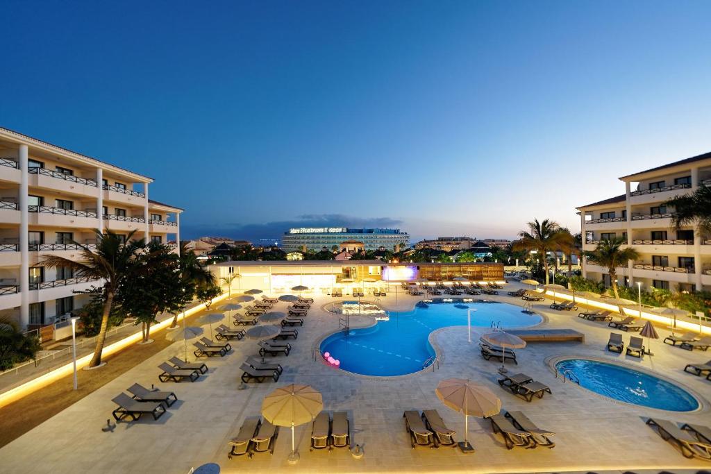 uma piscina com cadeiras e guarda-sóis num resort em Hotel Parque La Paz em Playa de las Americas