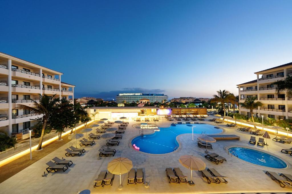 una piscina con sillas y sombrillas en un complejo en Hotel Parque La Paz, en Playa de las Américas