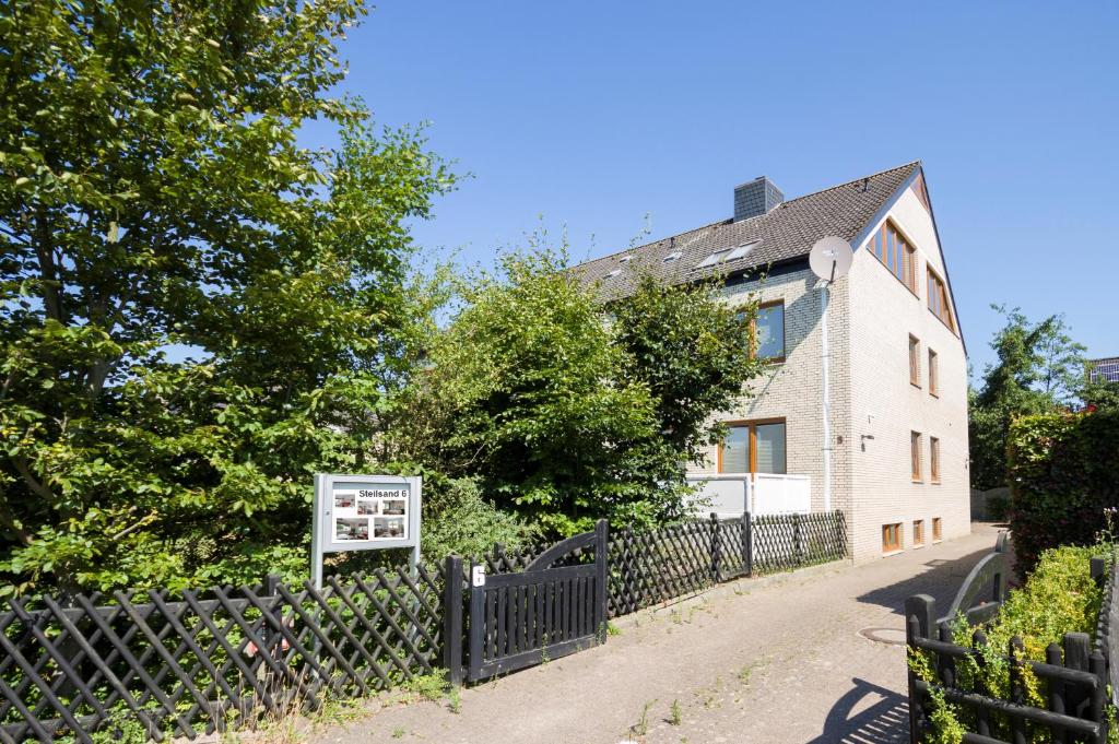 una casa con una valla negra junto a una carretera en Apartments Christiansen, en Cuxhaven