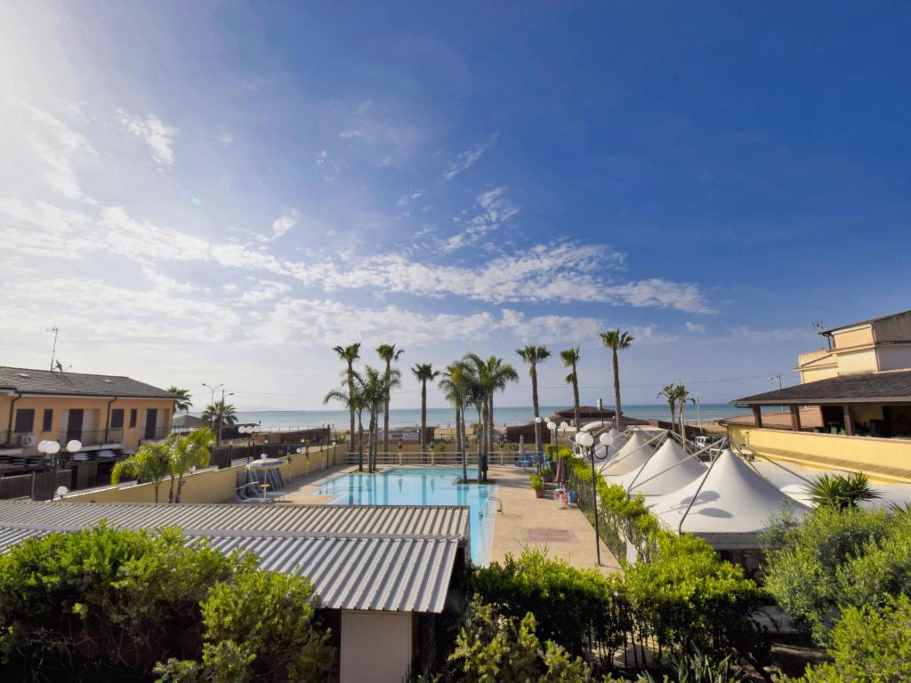 uitzicht op het zwembad van het resort met palmbomen bij Apartment L'Ancora-1 by Interhome in Porto Empedocle