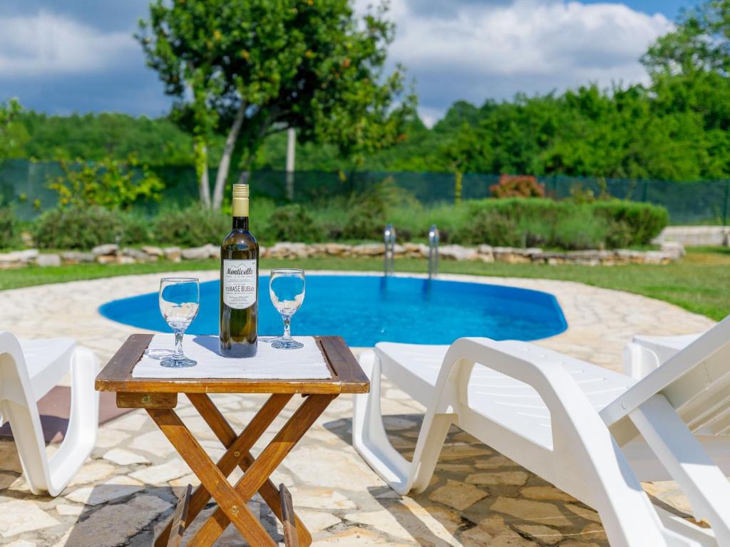 a bottle of wine on a table with two wine glasses at Holiday Home Villa Malini by Interhome in Boškari