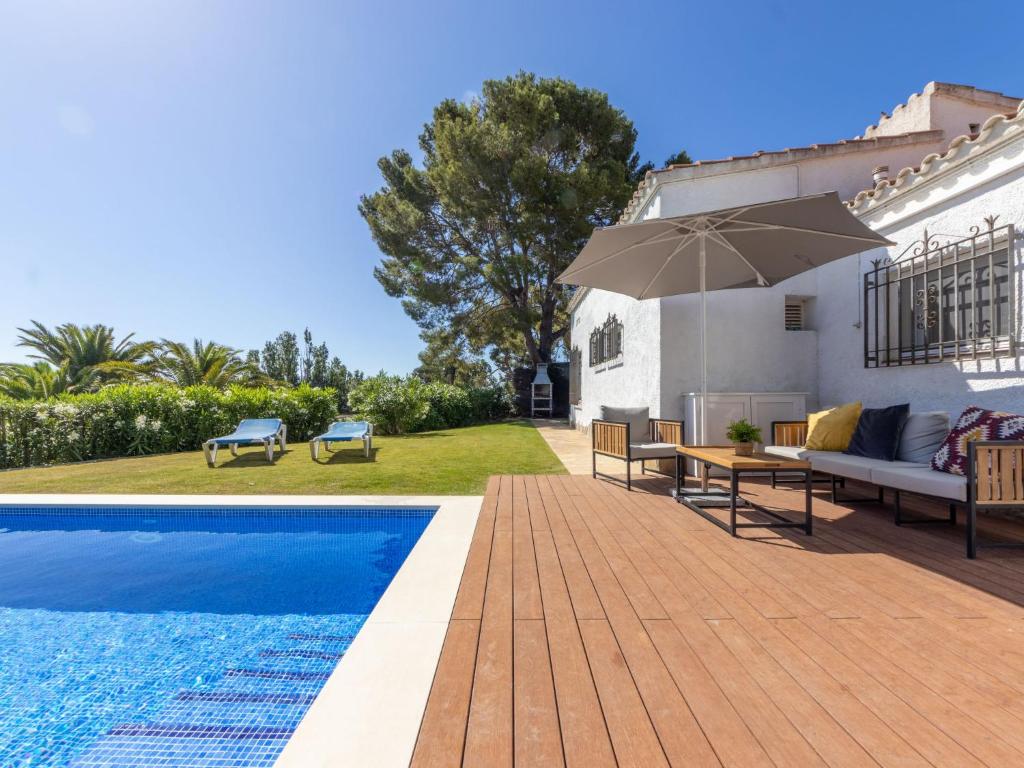 a swimming pool with a table and an umbrella next to a house at Villa Villa Valencia by Interhome in Cambrils