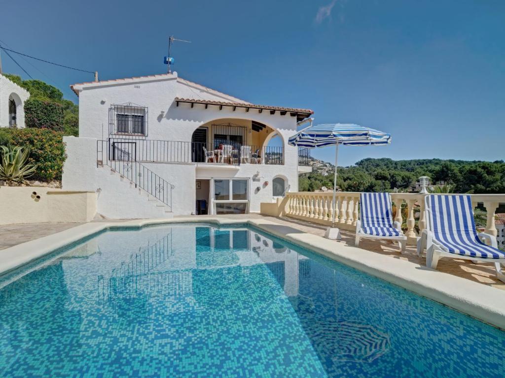 a swimming pool with two chairs and a house at Holiday Home La Repere by Interhome in Benissa