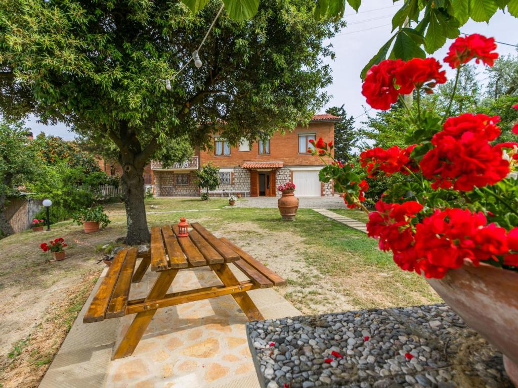un banc en bois dans une cour ornée de fleurs rouges dans l'établissement Holiday Home Miranda by Interhome, à Villamagna