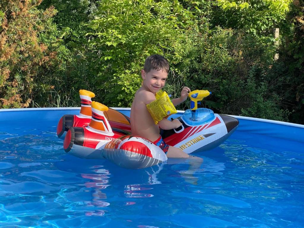 un joven sentado en un bote inflable en una piscina en Kolokán vendégház, en Sarud