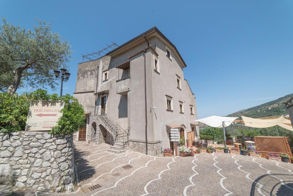 a large stone building with a table and an umbrella at Il Casale del Golfo in Vico Equense