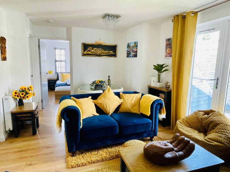 a living room with a blue couch with yellow pillows at Captains Rest - 2 bedroom apartment in the heart of Brixham in Brixham