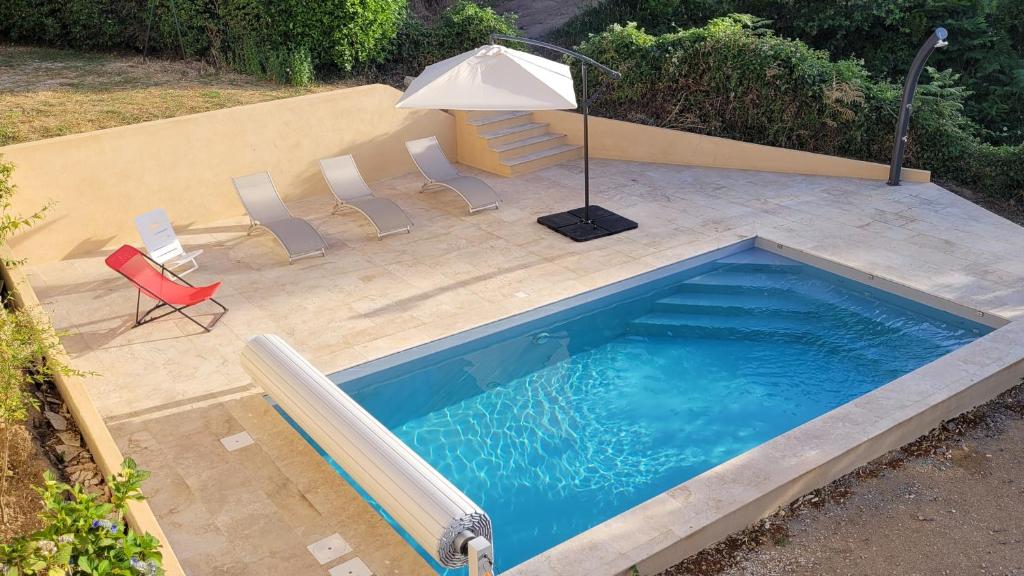 a swimming pool with chairs and an umbrella at Maison avec piscine entre mer et montagne in Muro