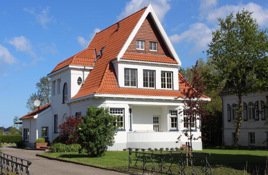 a white house with an orange roof at Villa 1909 in Krummhörn