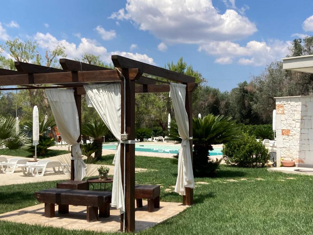 a wooden pergola in a yard with a pool at Casa Antonia in Mesagne