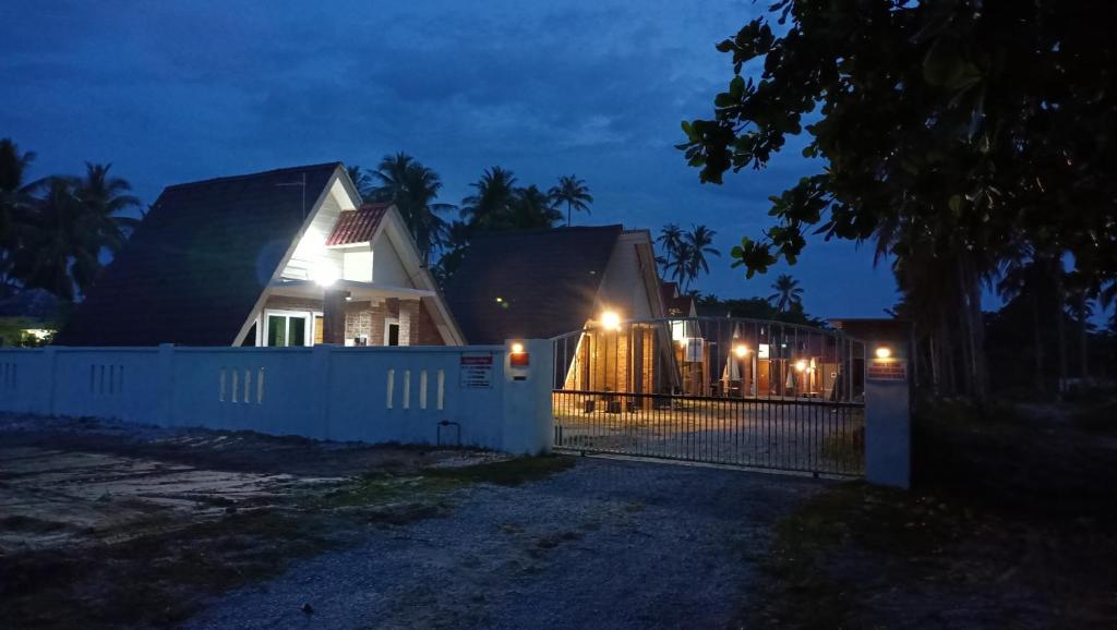 une maison avec une clôture devant elle la nuit dans l'établissement Zainab Cottage, à Pasir Puteh