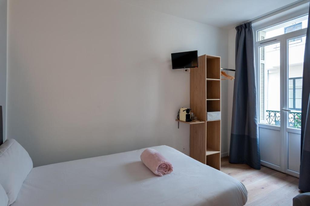 a small bedroom with a bed and a window at Hotel l'Hotera in Cannes