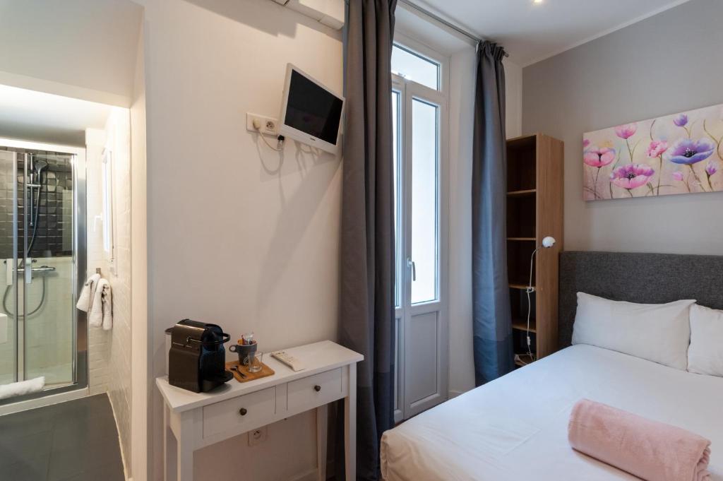 a small bedroom with a bed and a window at Hotel l'Hotera in Cannes