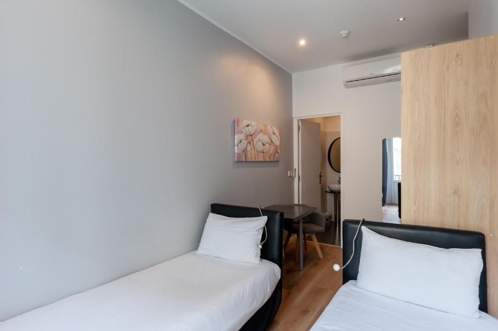a bedroom with two beds and a table in it at Hotel l'Hotera in Cannes