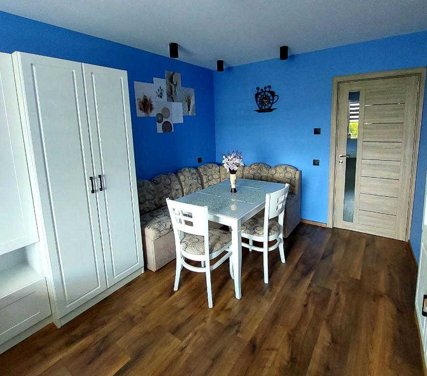 a dining room with a white table and blue walls at Zara Apartment in Gorna Oryakhovitsa