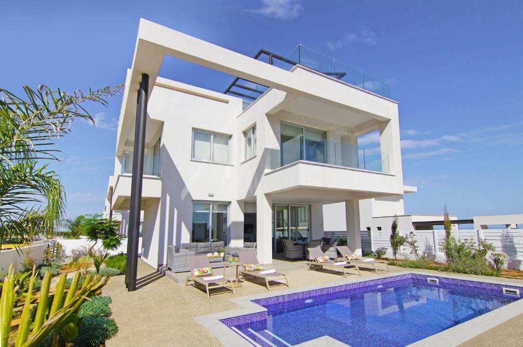 eine weiße Villa mit einem Swimmingpool davor in der Unterkunft Villa Amelia in Paralimni