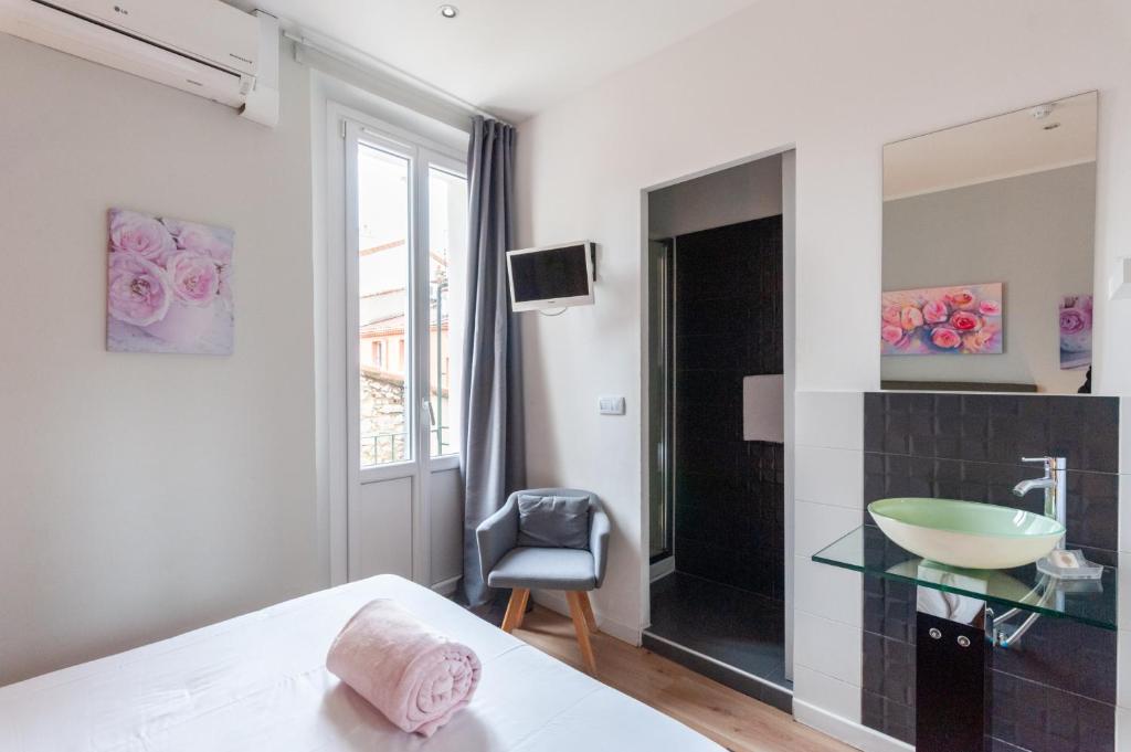 a bedroom with a bathroom with a sink and a mirror at Hotel l'Hotera in Cannes