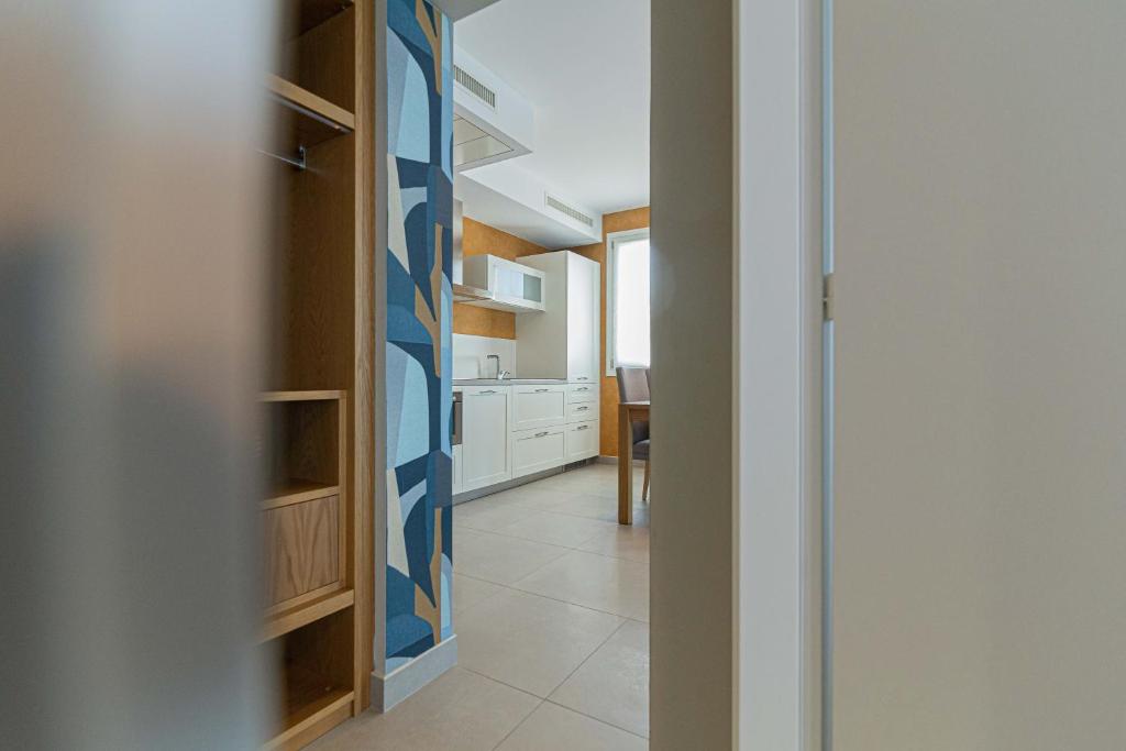 a hallway with a door to a kitchen with a kitchen at Mosella Suite Hotel in Sottomarina
