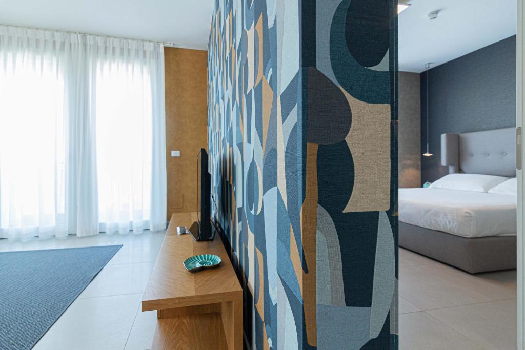 a hotel room with a bed and a television on a wall at Mosella Suite Hotel in Sottomarina
