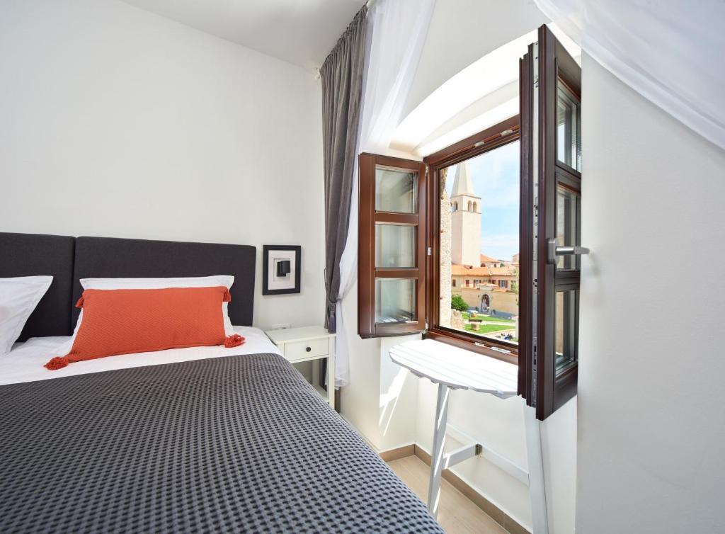 una camera con letto, finestra e sedia di Cardo Apartments a Poreč (Parenzo)