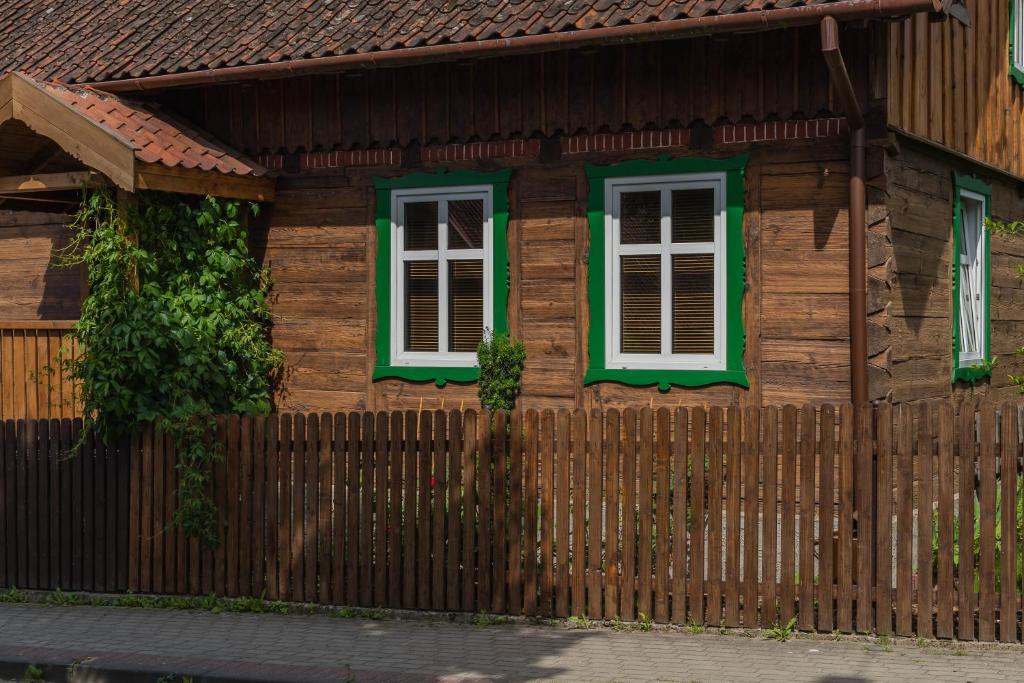 a wooden house with green windows and a fence at Dom w Krutyni in Krutyń
