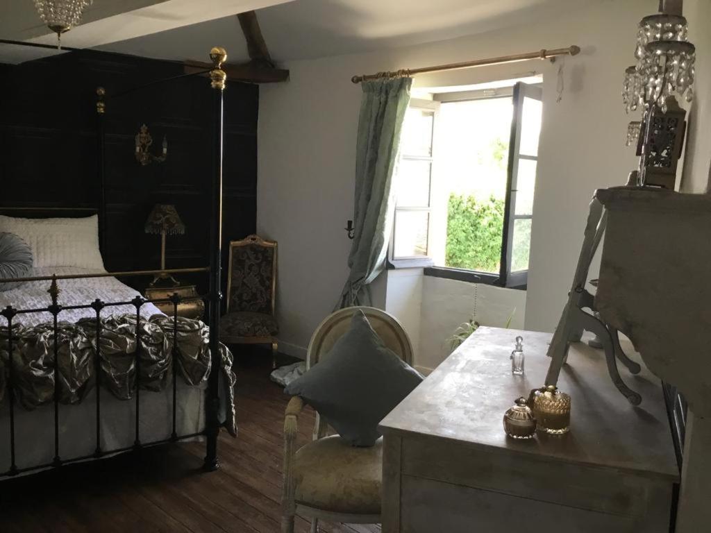 a bedroom with a bed and a chair and a window at La Cour Blanche in Verteuil-sur-Charente