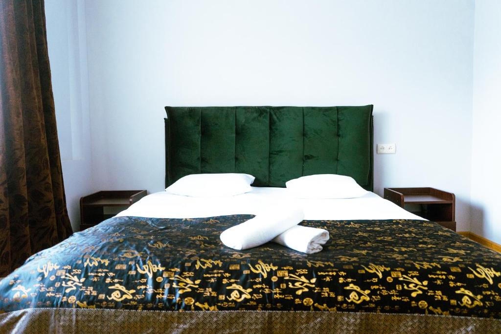 Hotel White House في تبليسي: غرفة نوم مع سرير مع اللوح الأمامي الأخضر