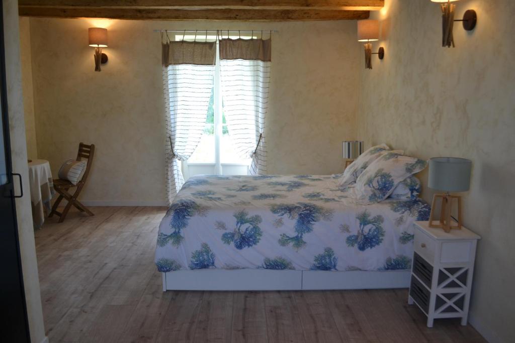 ein Schlafzimmer mit einem Bett mit einer blauen und weißen Decke in der Unterkunft Escale à Villeperdue chambre Hellulaug in La Barillonnerie
