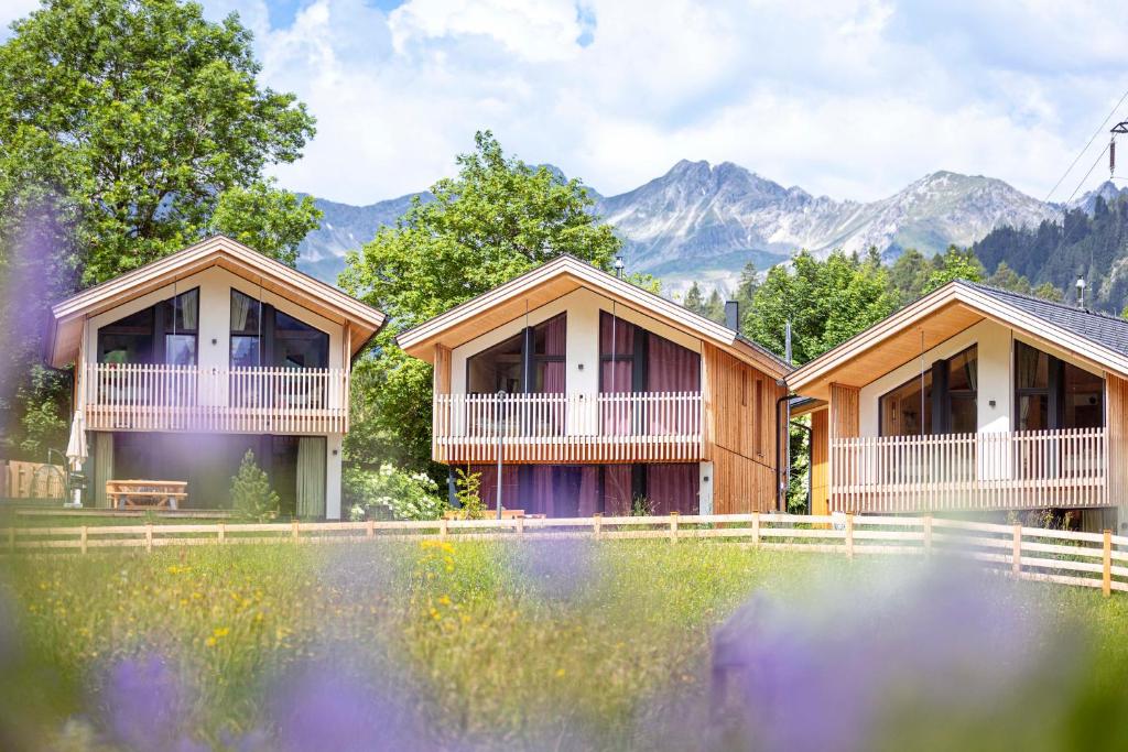 a row of cottages with mountains in the background at Alpenchalets Biberwier Zugspitze by ALPS RESORTS in Biberwier