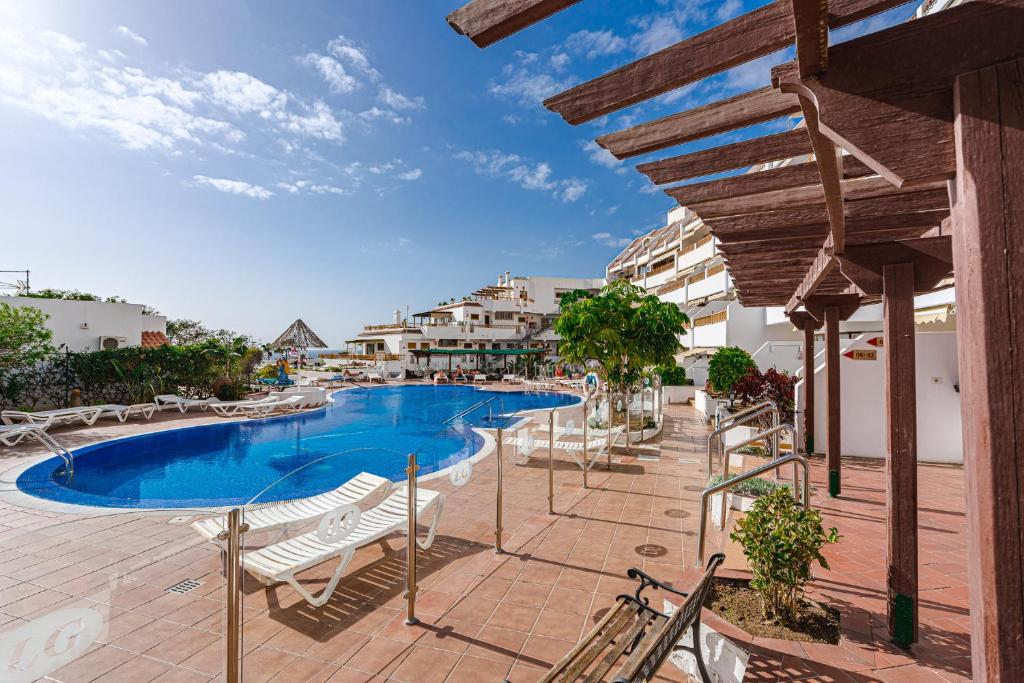 een resort met een zwembad en ligstoelen bij Lovely studio, La Pinta beach, Complex Los Geranios in Adeje