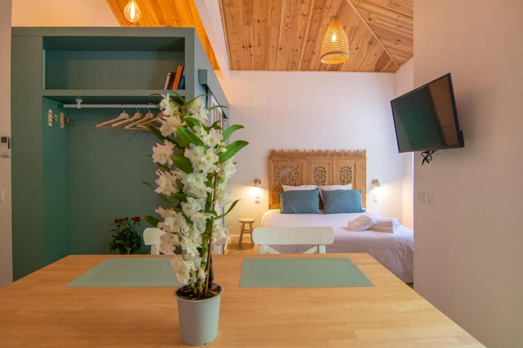 a room with a bed and a table with a vase with flowers at Welcôm Apparts-chic et intimiste-100m du Port in La Teste-de-Buch