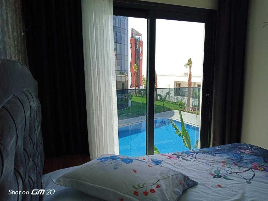 a bedroom with a view of a swimming pool through a window at Ege Birlik in Kuşadası