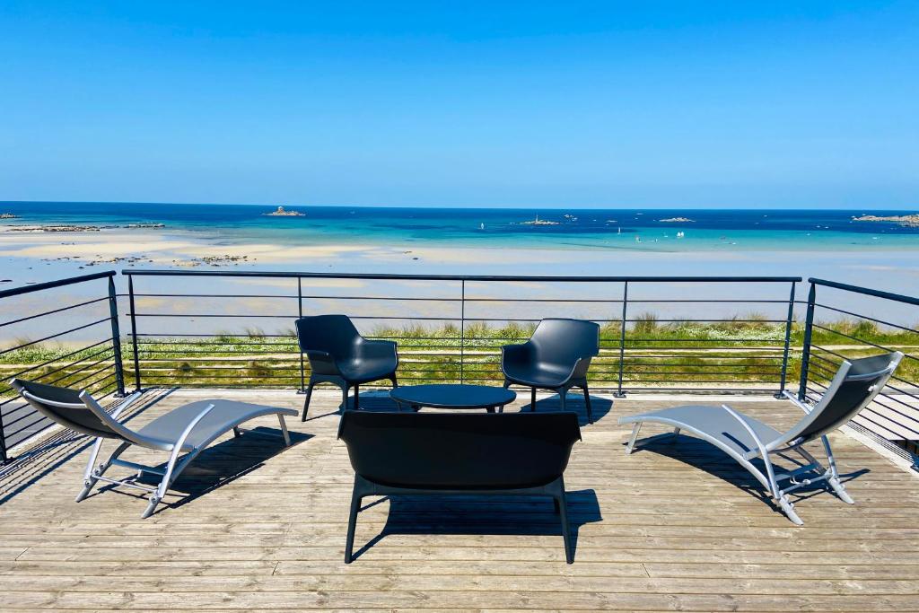 プルエスカにあるVilla de la plage de Plouescatのビーチの景色を望むパティオ(椅子、テーブル付)