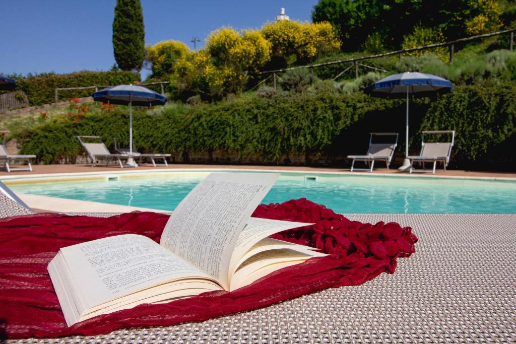 a book laying on a blanket next to a swimming pool at Agriturismo Poggio Pistolese in Montaione