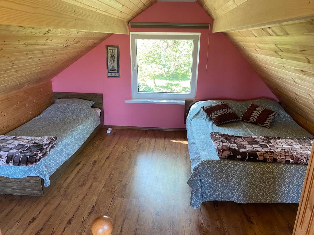 2 camas en una habitación con paredes rosas y ventana en Strazdiņi, en Saraiķi