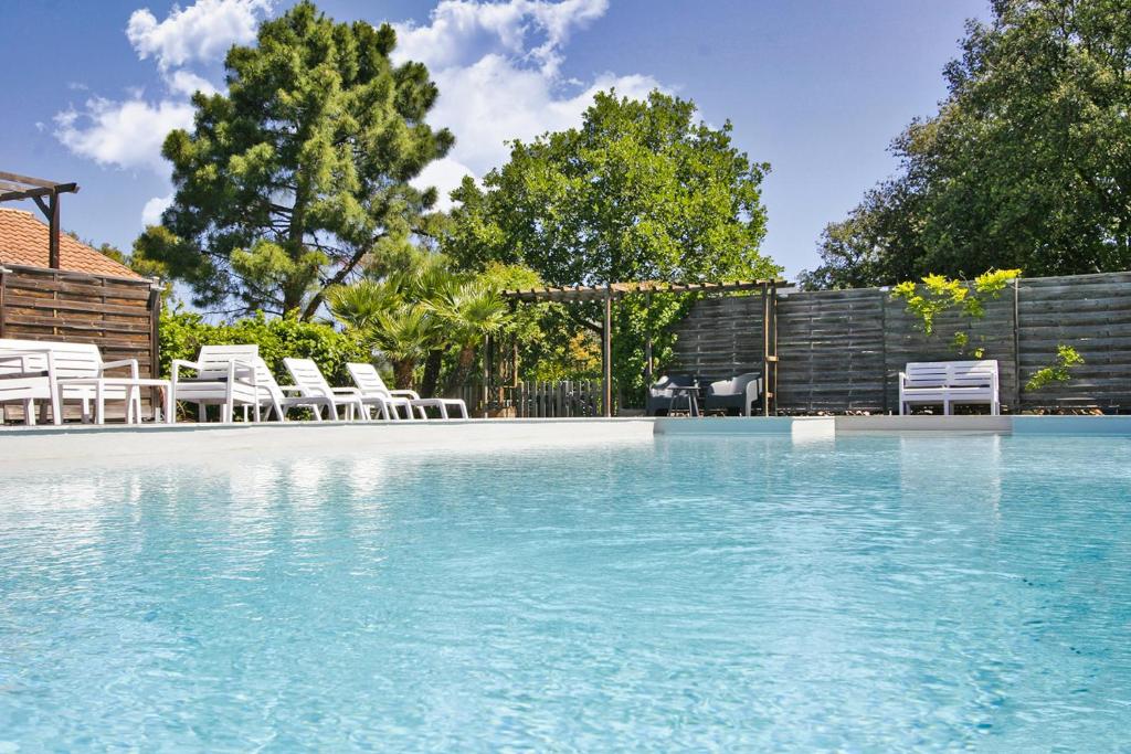 uma piscina com cadeiras brancas e uma cerca em CASA di u cuginu em Calenzana