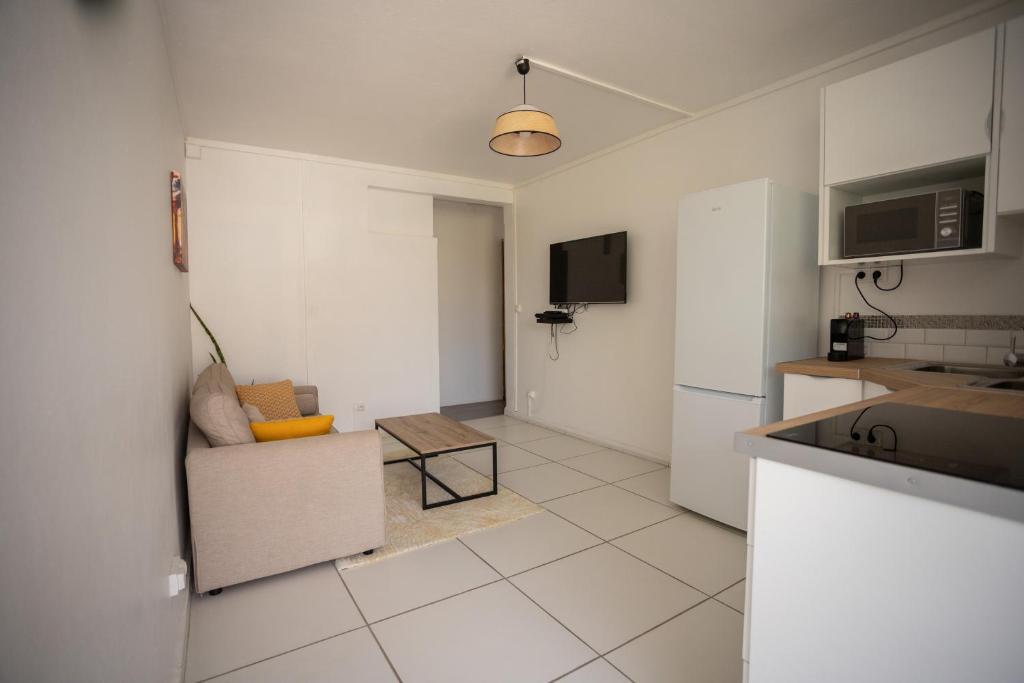 a white kitchen with a couch and a refrigerator at Place de la Cathédrale de Pointe à Pitre in Pointe-à-Pitre