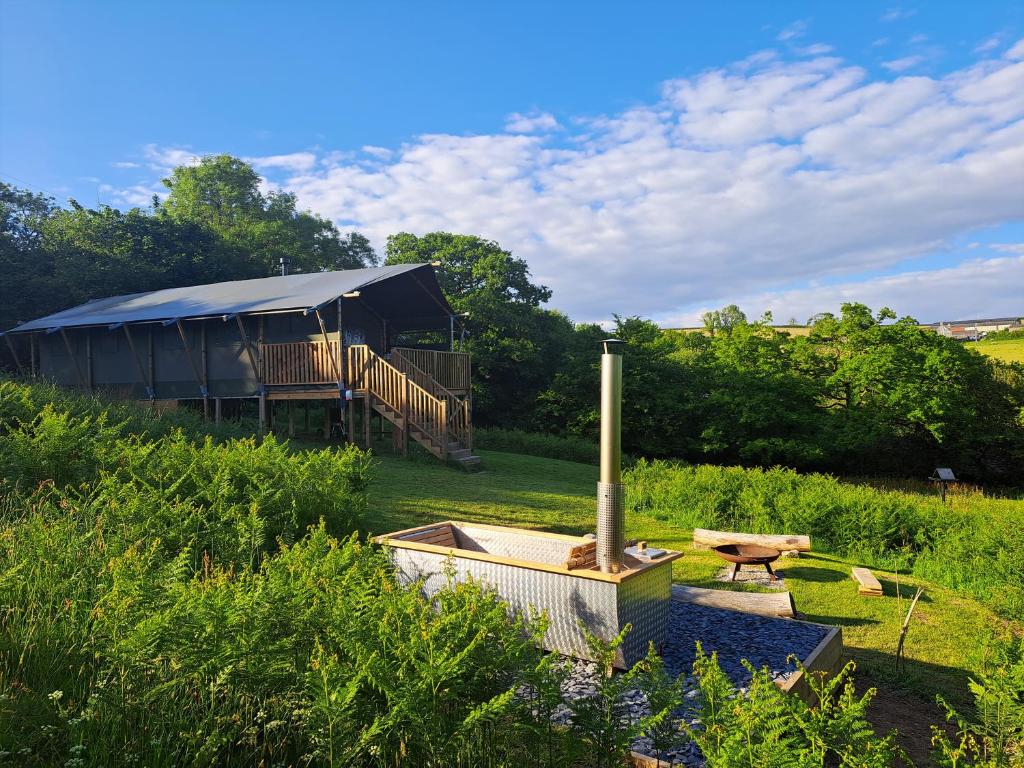 a large building with a tent in a field at Brackenhill Glamping - Safari Tent with Hot Tub - Sleeps 6 in Ivybridge