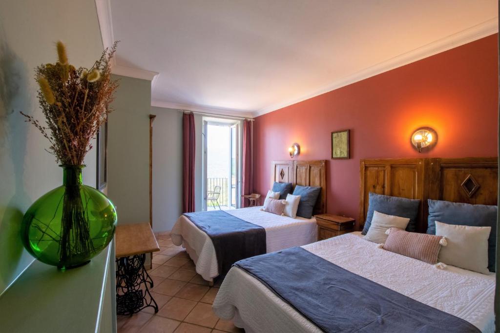 a hotel room with two beds and a vase with flowers at Hotel La Terrasse in Zonza