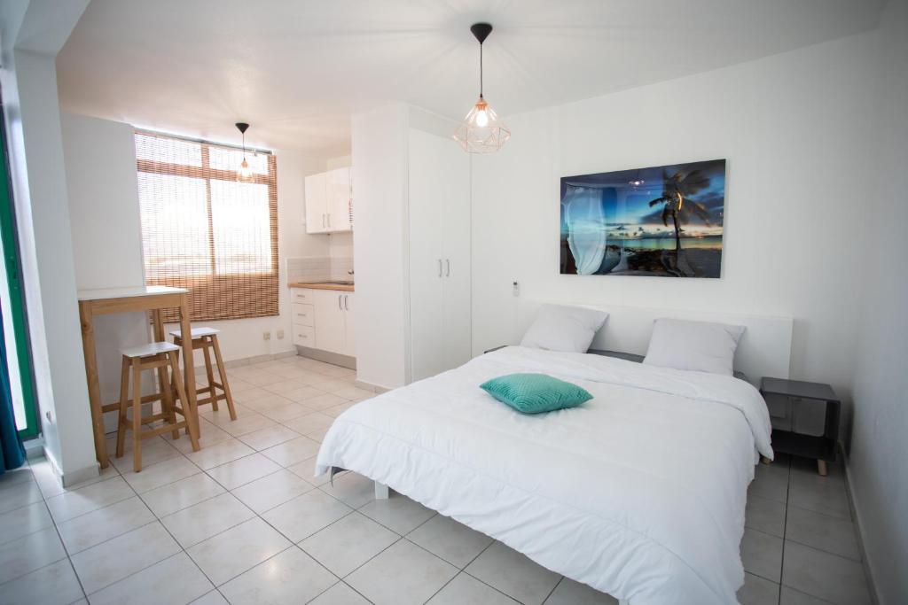 a white bedroom with a bed and a kitchen at BOULEVARD LEGITIMUS in Pointe-à-Pitre