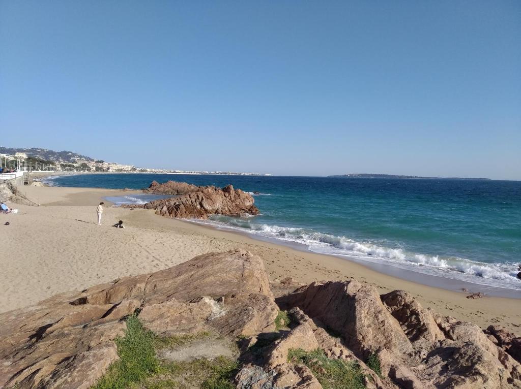 a beach with rocks and the ocean on a sunny day at Sainte Rosalie in Cannes