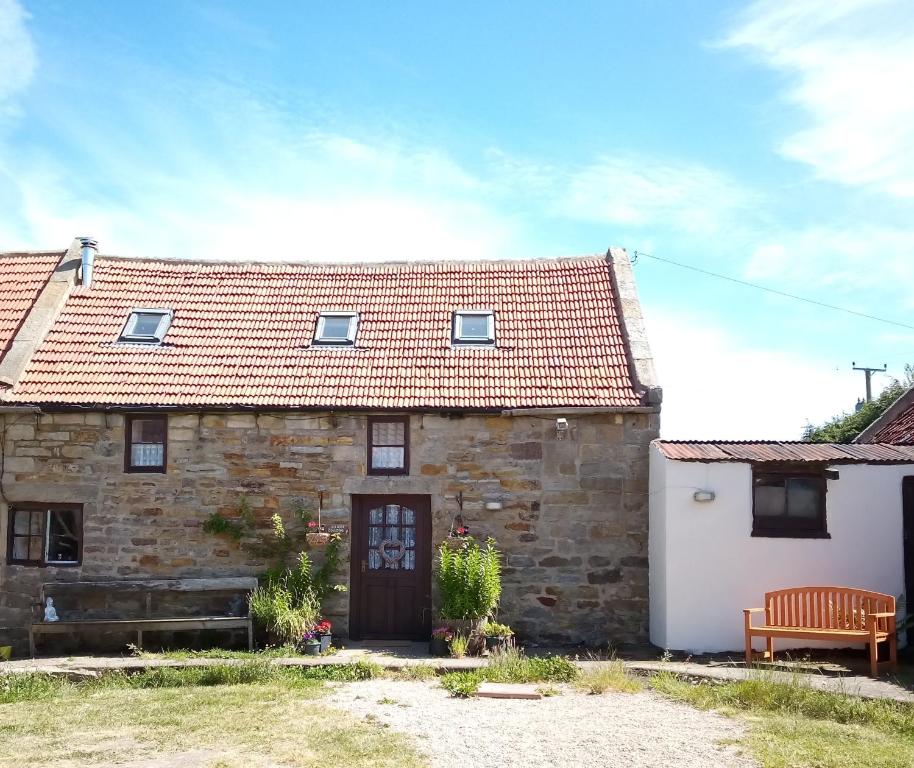 una vieja casa de piedra con un banco delante de ella en LAVENDER COTTAGE en Whitby