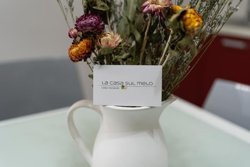 Eine weiße Vase mit einem Blumenstrauß. in der Unterkunft La Casa Sul Melo in Matera
