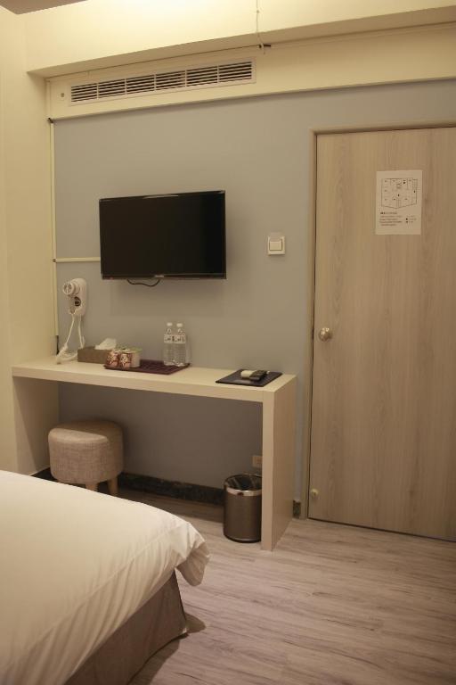 a bedroom with a desk with a television and a bed at Prince Hotel in Chiayi City